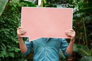 Person holding a large, empty, pink comment box in front of their face