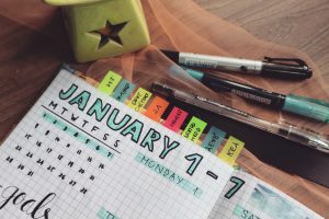 Planner for January with room to write goal. Pens and sticky note labels also pictured.