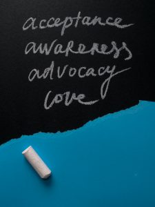 Four words written in chalk on a black board acceptance, awareness, advocacy, love.